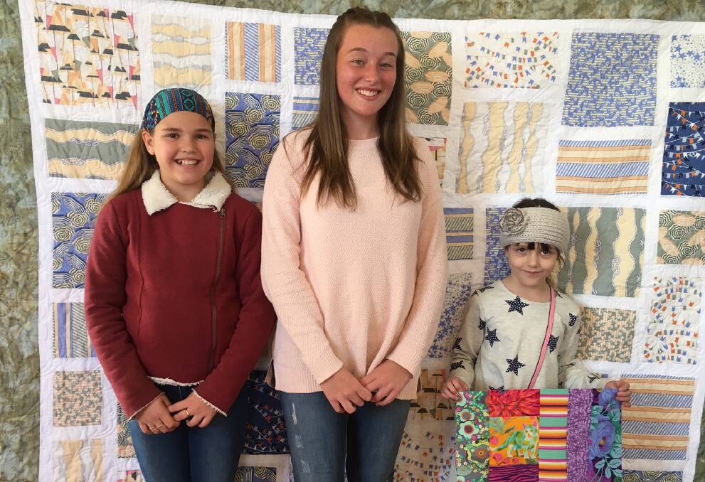 SHOWCASE: Singleton Quilters junior members Meg Meyers, Emily Knight and Kirby Hayes standing in front of Emily’s quilt made when she was 13 years old. The trio is looking forward to the upcoming Quilters show.