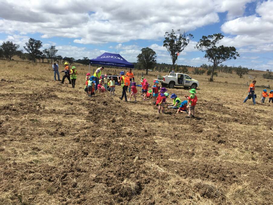 Singleton Heights Pre-School students busy planting the seedlings they grew for Ravensworth mine.