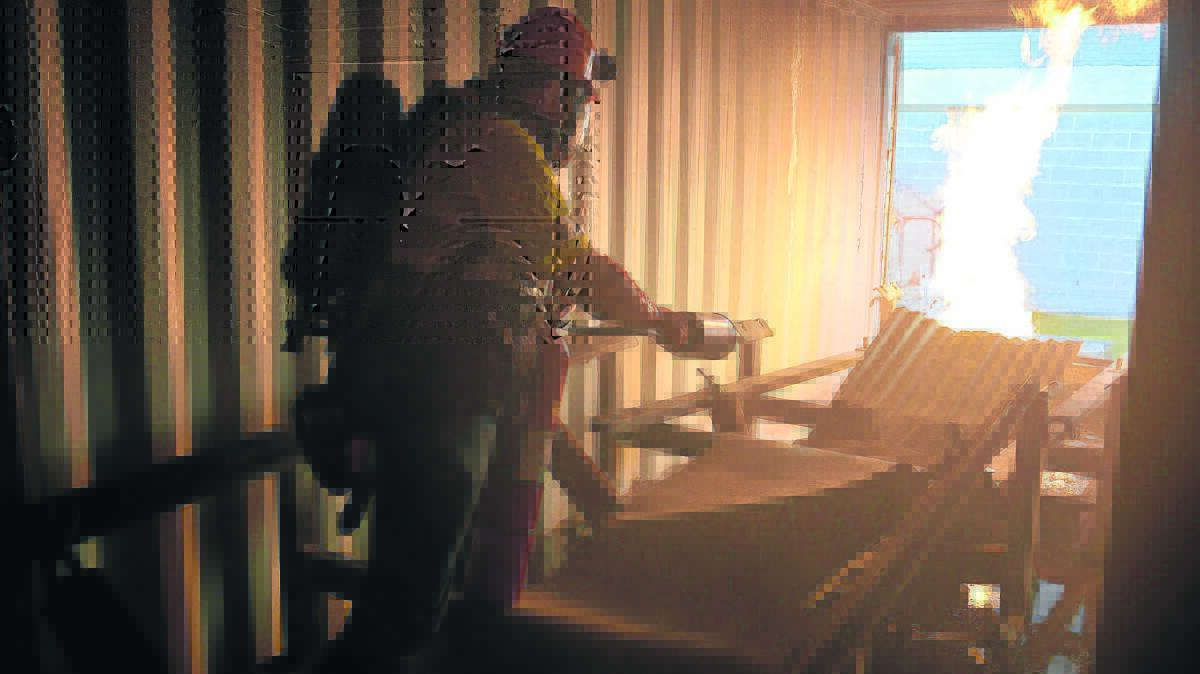 REALISTIC ENVIRONMENT:  (Pictured right) Clayton Moore extinguishes a fire on a conveyor belt  inside a shipping container that replicates a mine shaft at the Hunter Valley Mines Rescue facility,  it was one of the scenarios that brigadesmen were tested on Friday.