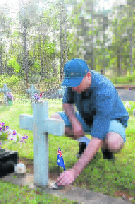FAMILY CONNECTION: Tony Garland places an Australian flag on his great grandfather Soloman Leslie Garland’s grave  at Sedgefield Cemetery. 
