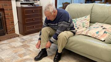 A senior sitting on a couch, tying his shoe laces. File picture
