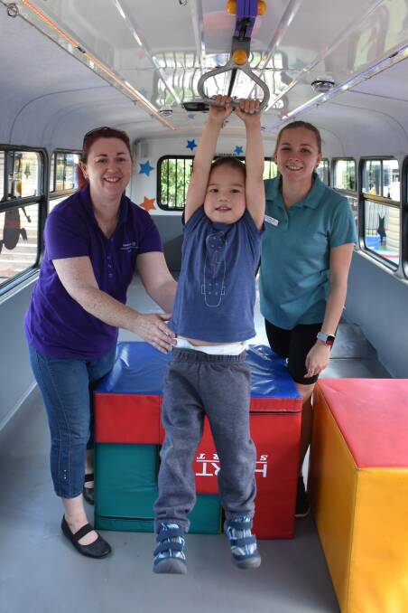 PLAYTIME: Aeron Gould, Early Links Inclusion Support Service, with three-year-old Zoen Xu and Brooke Dicker inside the Big Yellow Bus that will be at the Singleton Youth Venue  each Thursday morning during school term.