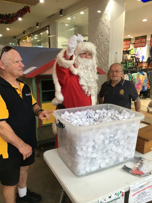 Santa draws the winning ticket. with Rotarian Bob Wood and Barry Cox. Photo supplied.