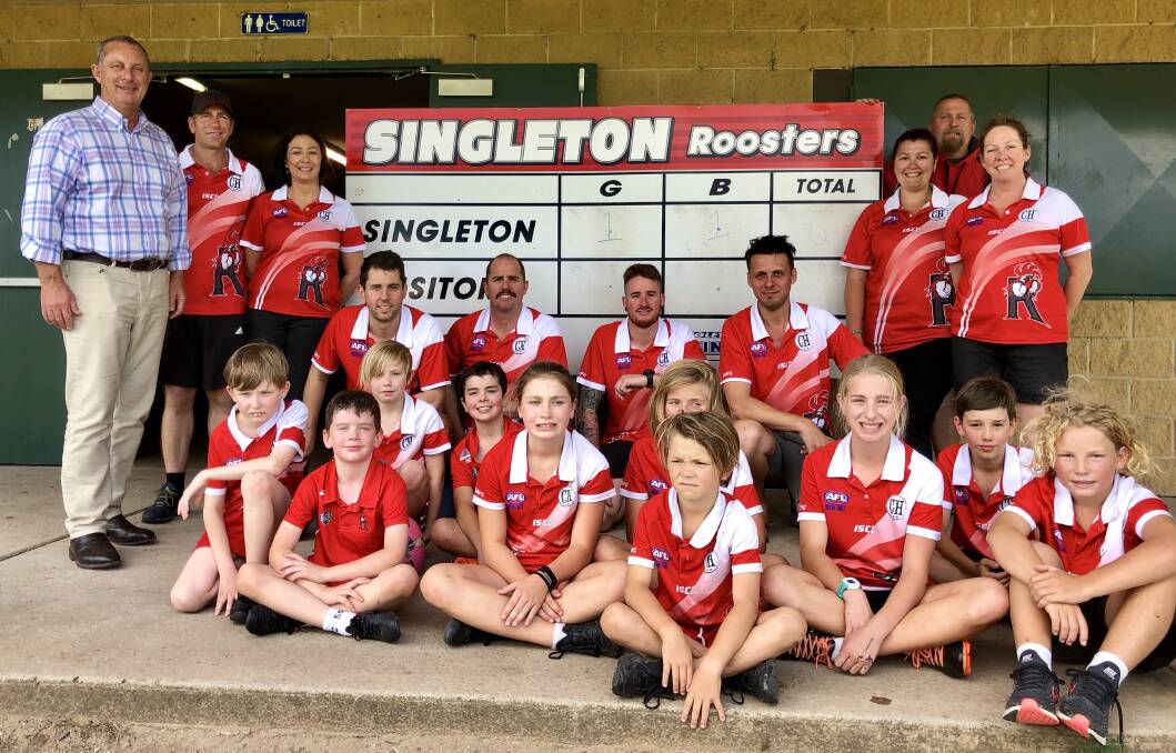 ALL SMILES: Michael Johnsen with members of the Singleton Roosters AFL Club  in front of the soon to be replaced scoreboard.