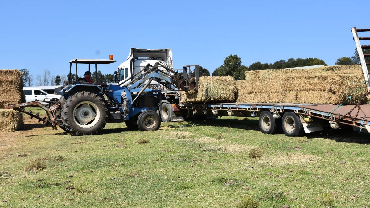Unload one semi and load another as the donated hay is distributed in the local district.