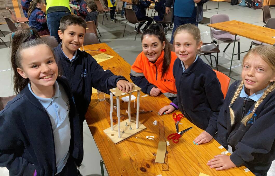 Yancoals Lucy Griffiths and students from Muswellbrook Public School with their structure to test on the University of Newcastles earthquake simulator at the primary school Science and Engineering Discovery Day. Photo supplied.