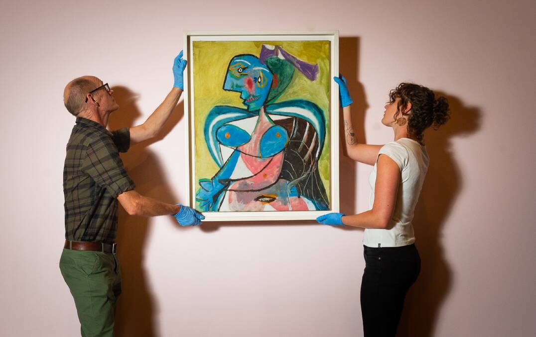Exhibition installers Ben Taylor and Ruby Rossiter hang Pablo Picasso's L'Artesienne: Lee Miller, part of the Matisse Picasso exhibition at the National Gallery of Australia. Picture: Elesa Kurtz