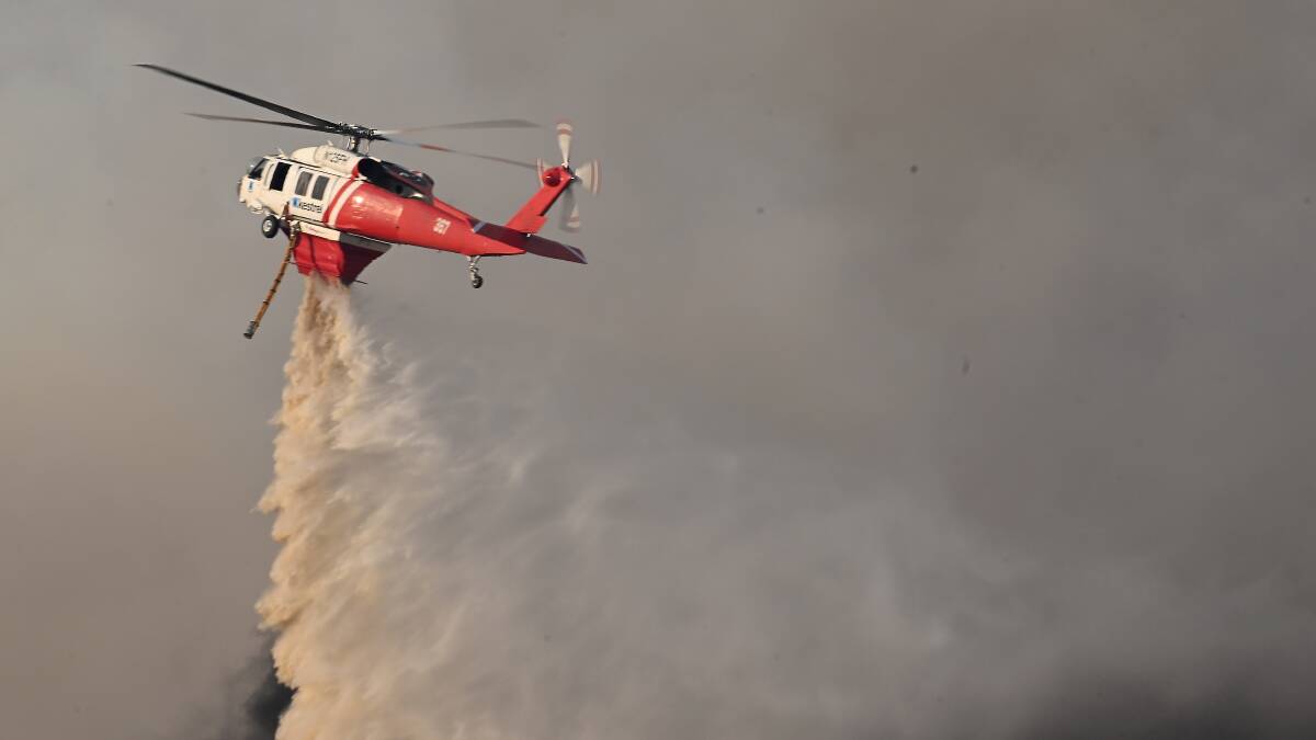 A firefighting helicopter drops a load of water on the fire near Buangor on February 22. Picture by Lachlan Bence