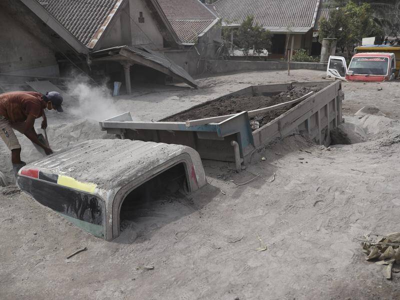 A man inspects a truck buried in ash following the eruption of Mount Semeru in Java.
