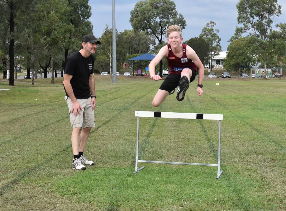 PROUD FATHER: Paul Brown guides his son Jordie, aged 13, over the hurdle.