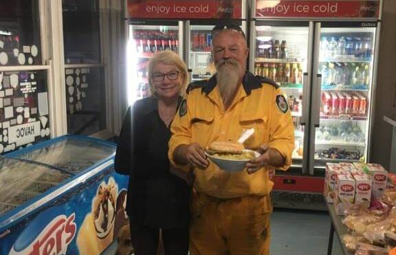 UNITED AS ONE: Grey Gum International Cafe owner Kim Grace pictured with one of many firefighters to have been fed at her shop.
