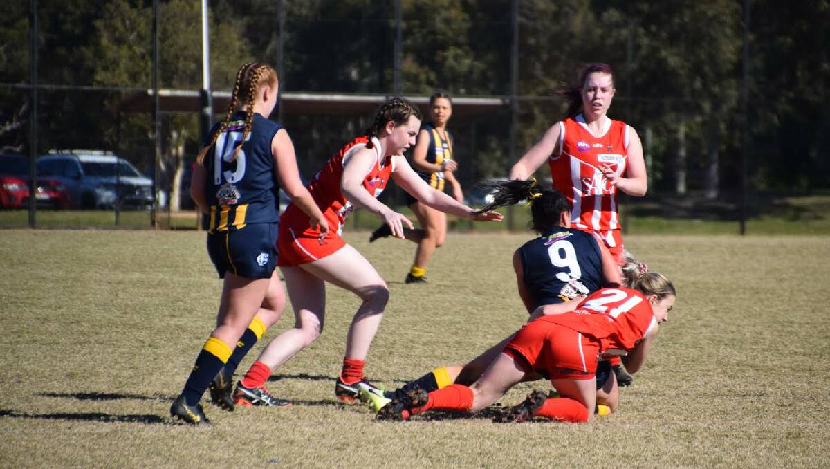 IN ACTION: Sisters Madeleine and Brenna Edsell assist teammate Tayla Gall on Saturday afternoon.
